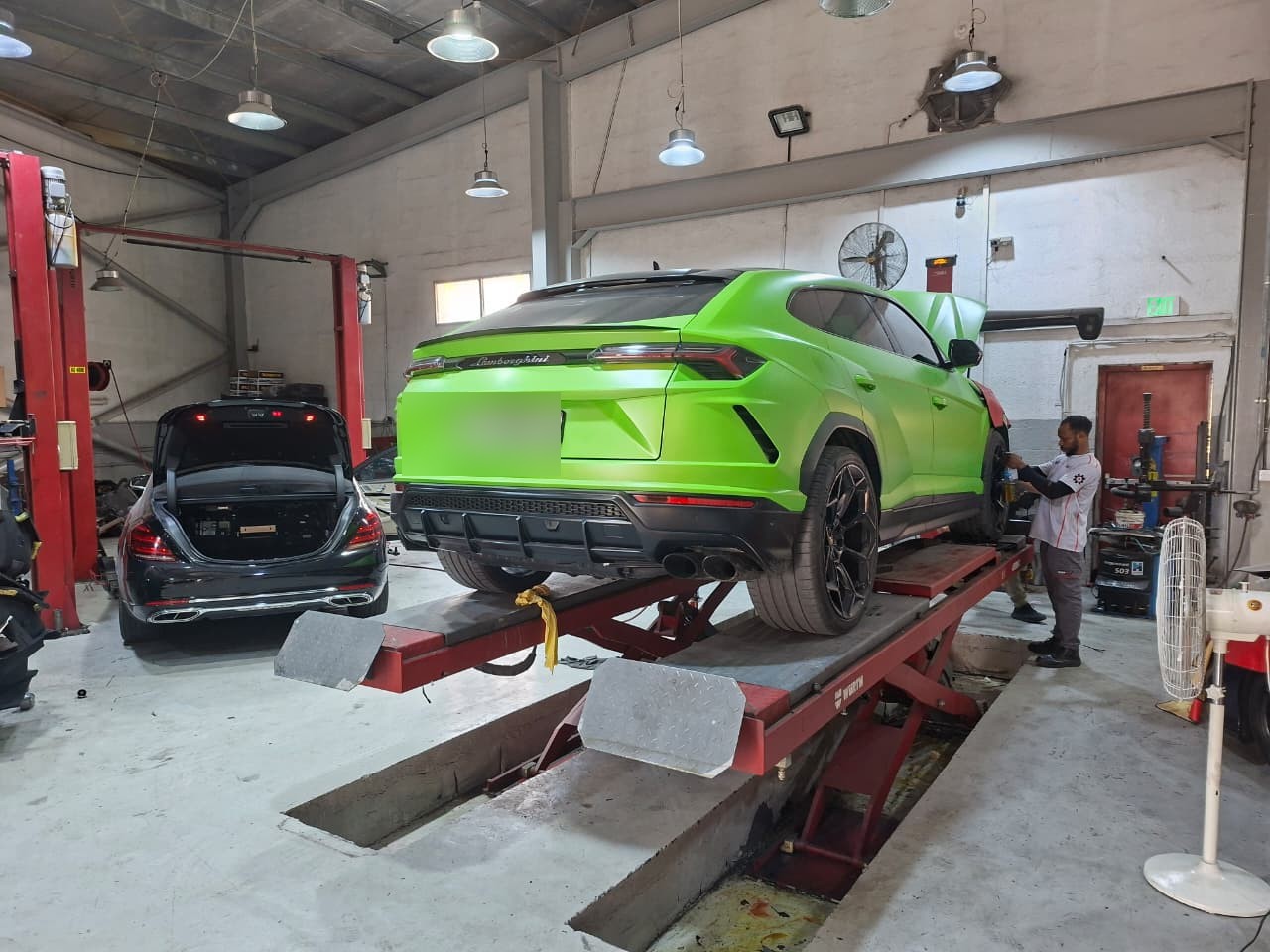 Green Lamborghini raised on a workshop lift